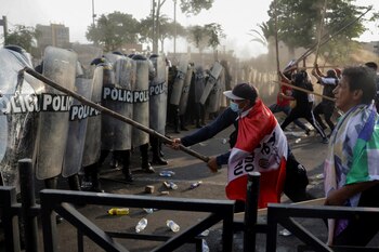Un protestante golpea al escudo